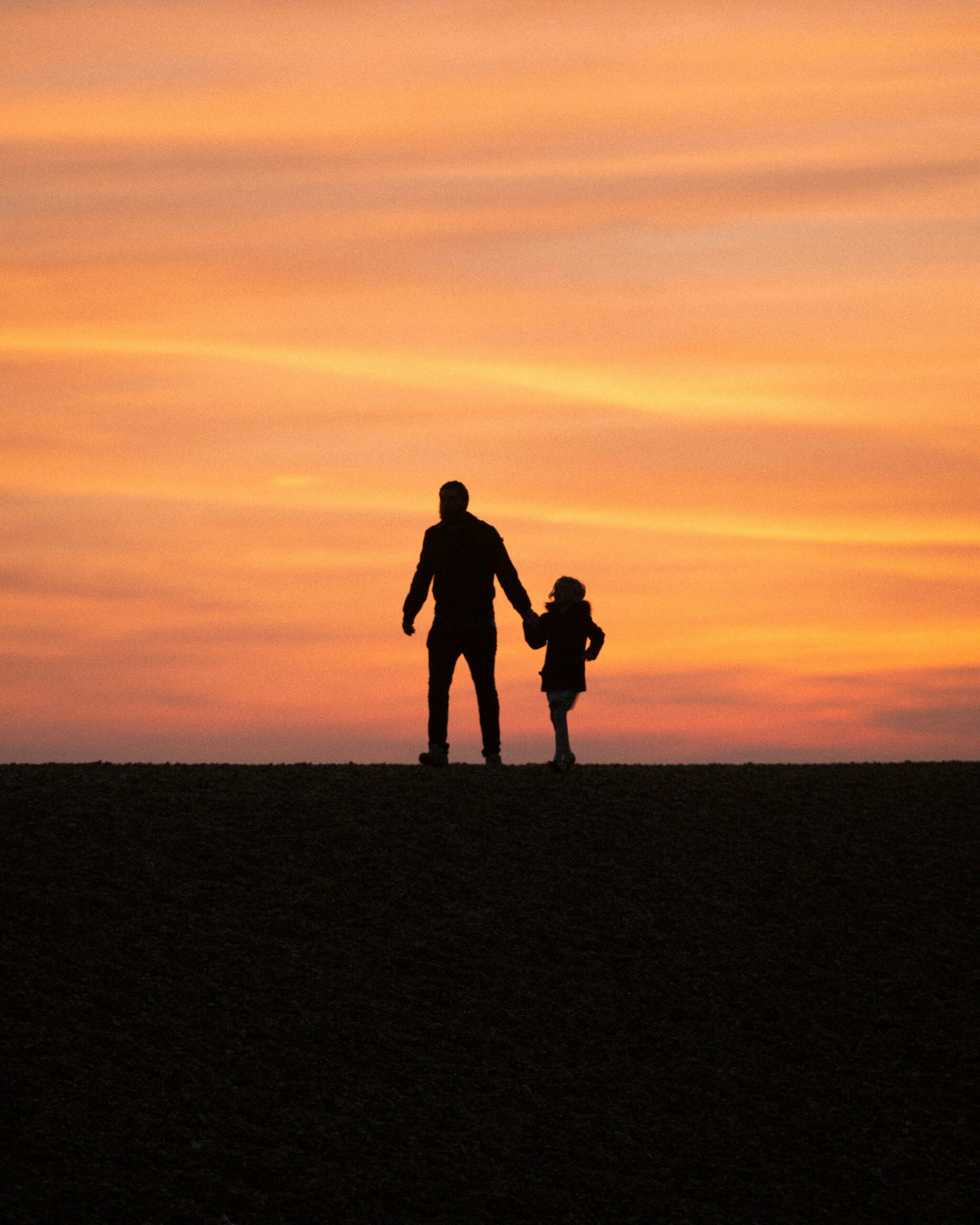 une silhouette d’un homme et d’une petite fille se tenant la main